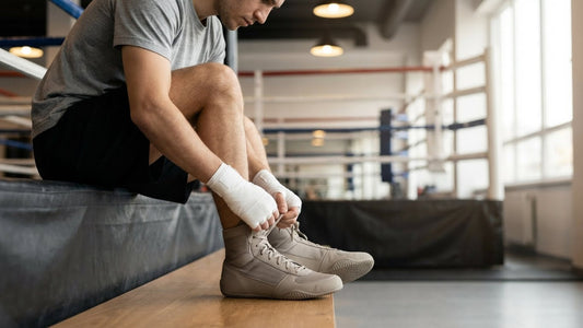 Beginner boxer in a gym lacing up boxing shoes next to a ring apron