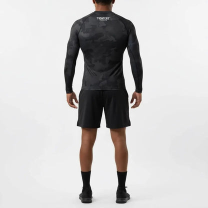 Person wearing a black camouflage long-sleeve shirt and shorts on a white background