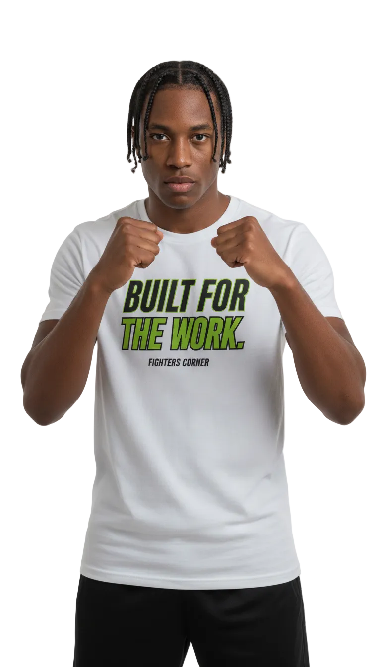 A man wearing a white graphic t-shirt with the text 'BUILT FOR THE WORK. FIGHTERS CORNER' in green and black, posed with fists raised against a light gray background.